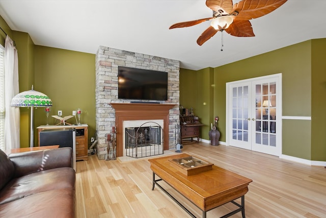 living room with a fireplace, wood finished floors, baseboards, and french doors