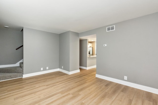 unfurnished room with stairs, light wood-style flooring, baseboards, and visible vents