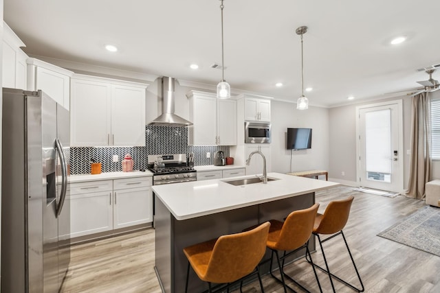 kitchen featuring a sink, decorative backsplash, stainless steel appliances, white cabinets, and wall chimney exhaust hood