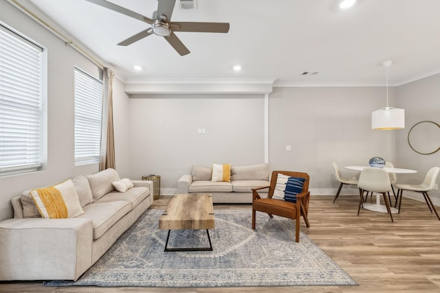 living area featuring recessed lighting, light wood-type flooring, baseboards, and crown molding