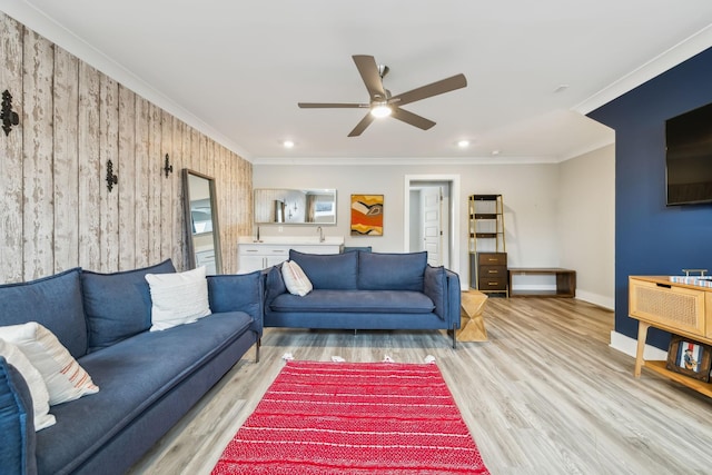 living area with ornamental molding, a ceiling fan, recessed lighting, light wood finished floors, and baseboards