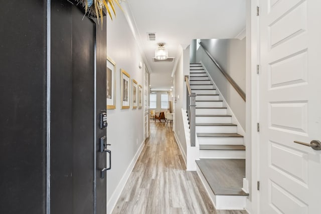 foyer entrance featuring light wood-type flooring, baseboards, visible vents, and stairs