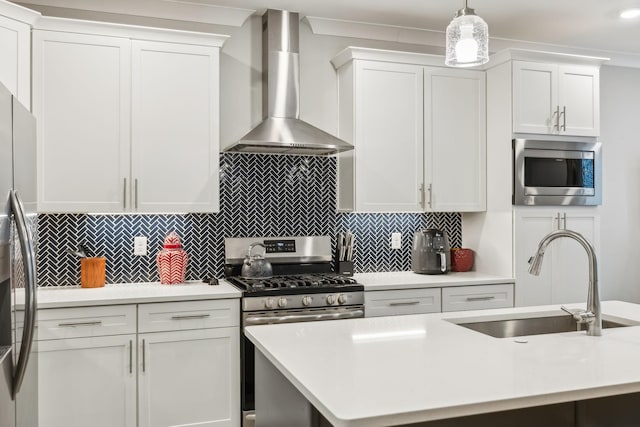 kitchen featuring light countertops, wall chimney range hood, appliances with stainless steel finishes, and a sink