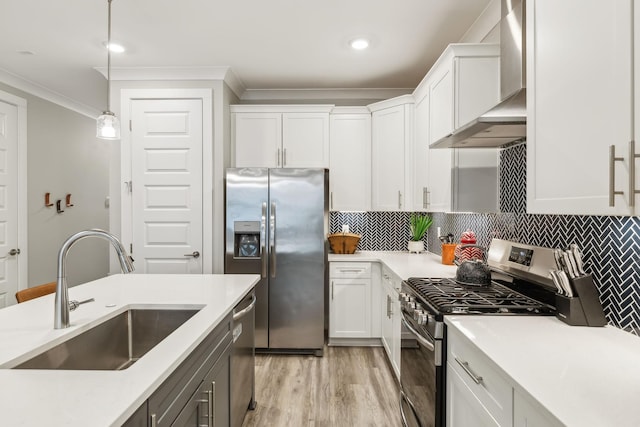 kitchen featuring wall chimney range hood, light countertops, ornamental molding, stainless steel appliances, and a sink