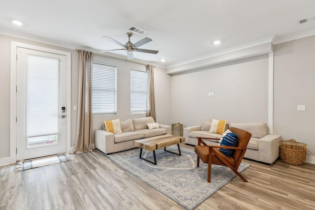 living area featuring light wood-type flooring, visible vents, and ornamental molding