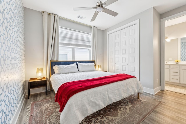 bedroom featuring visible vents, wallpapered walls, baseboards, wood finished floors, and a closet