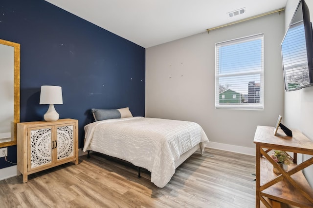 bedroom with baseboards, visible vents, and light wood finished floors