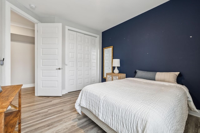 bedroom with a closet, light wood-style flooring, and baseboards