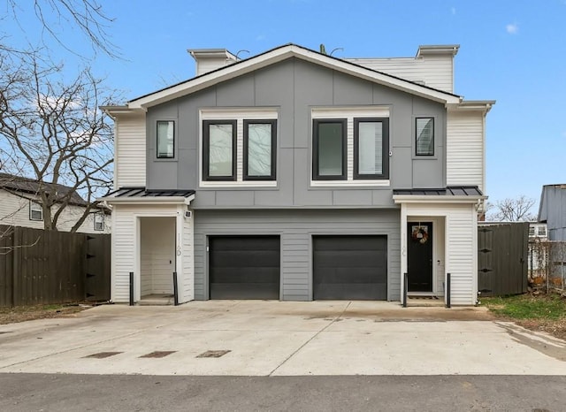 view of front facade featuring a garage, fence, board and batten siding, and a standing seam roof