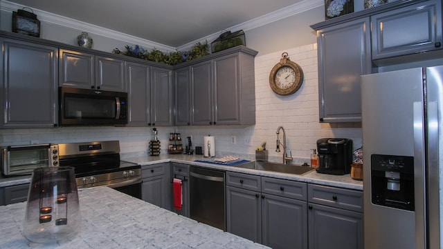 kitchen featuring a toaster, ornamental molding, decorative backsplash, appliances with stainless steel finishes, and a sink