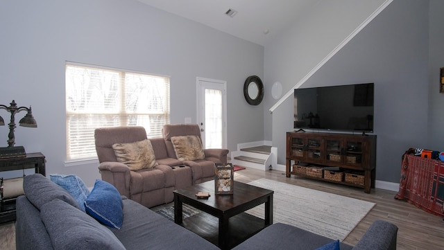 living room featuring baseboards, wood finished floors, visible vents, and high vaulted ceiling