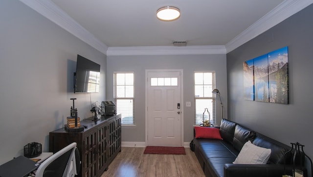 entryway with a wealth of natural light, visible vents, wood finished floors, and ornamental molding