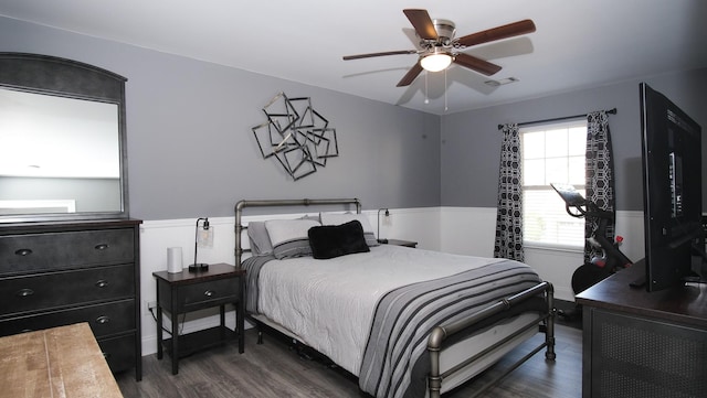 bedroom featuring visible vents, wainscoting, ceiling fan, and dark wood-style flooring