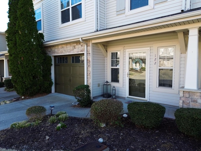 doorway to property featuring stone siding and an attached garage