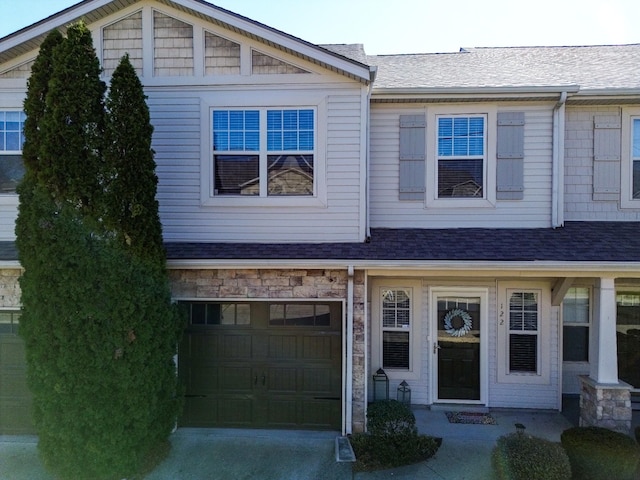 view of front of property with stone siding, driveway, and roof with shingles