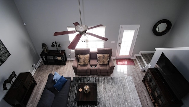 living room with a ceiling fan, baseboards, and wood finished floors