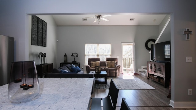 living room with ceiling fan, wood finished floors, visible vents, and baseboards