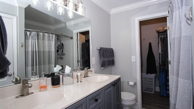 bathroom featuring a sink, toilet, double vanity, and crown molding