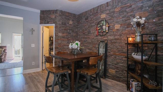 dining room with crown molding, wood finished floors, and baseboards