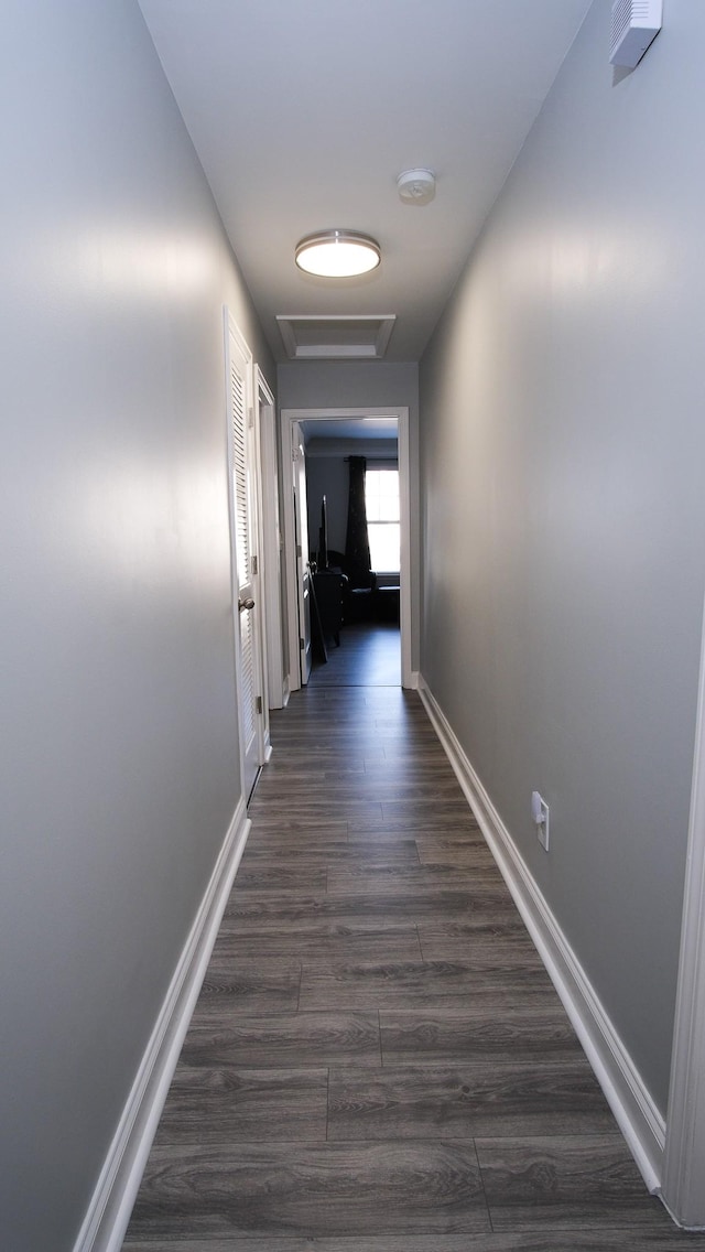 hall featuring dark wood finished floors, attic access, and baseboards