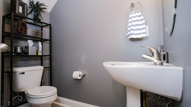 half bathroom with a sink, baseboards, and toilet