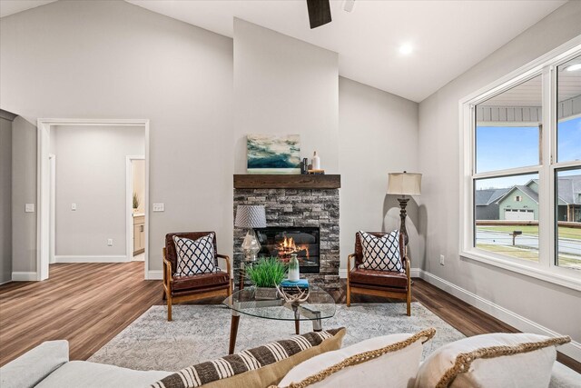 living room with a fireplace, wood finished floors, baseboards, and high vaulted ceiling