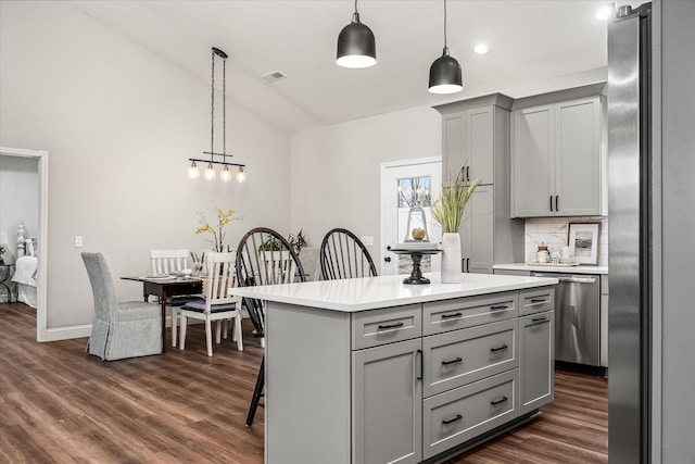 kitchen with gray cabinetry, stainless steel appliances, light countertops, lofted ceiling, and dark wood-style flooring