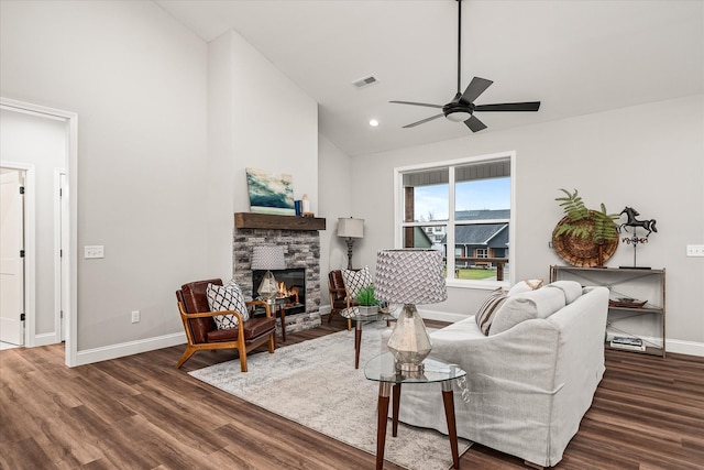 living area featuring visible vents, ceiling fan, baseboards, a stone fireplace, and wood finished floors