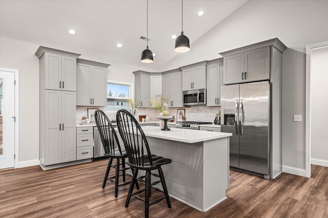 kitchen with a kitchen island, a breakfast bar, light countertops, gray cabinets, and stainless steel appliances