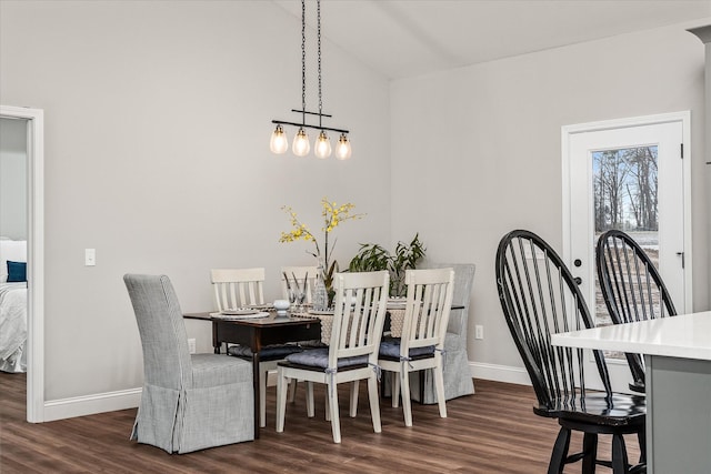 dining area featuring dark wood finished floors, baseboards, and vaulted ceiling