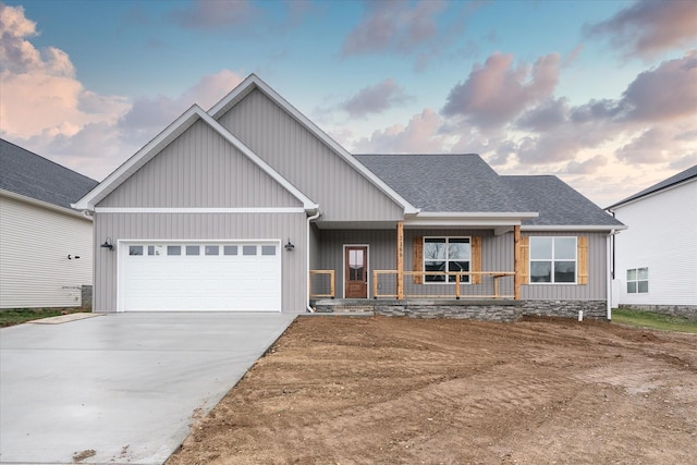 view of front of home with covered porch, an attached garage, concrete driveway, and roof with shingles