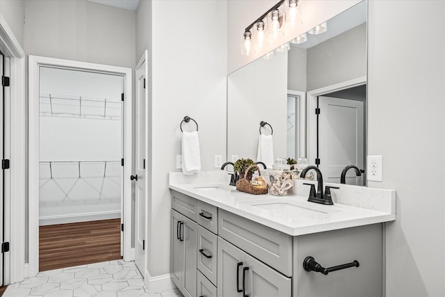 full bathroom featuring double vanity, a spacious closet, baseboards, and a sink