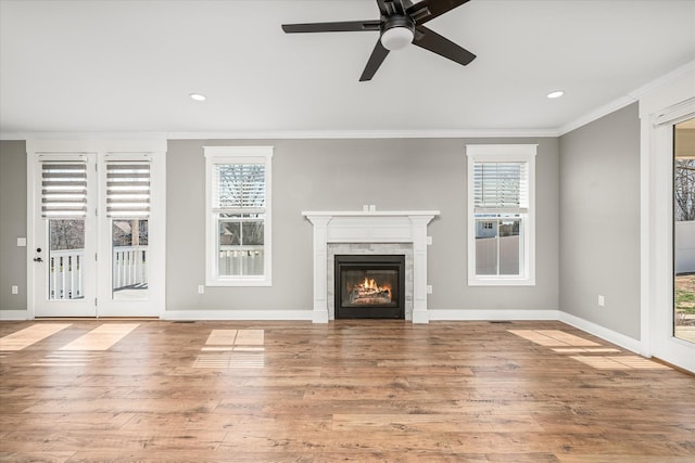 unfurnished living room featuring a wealth of natural light, wood finished floors, and crown molding