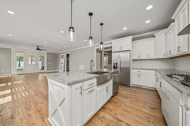 kitchen with white cabinets, ornamental molding, appliances with stainless steel finishes, and a sink