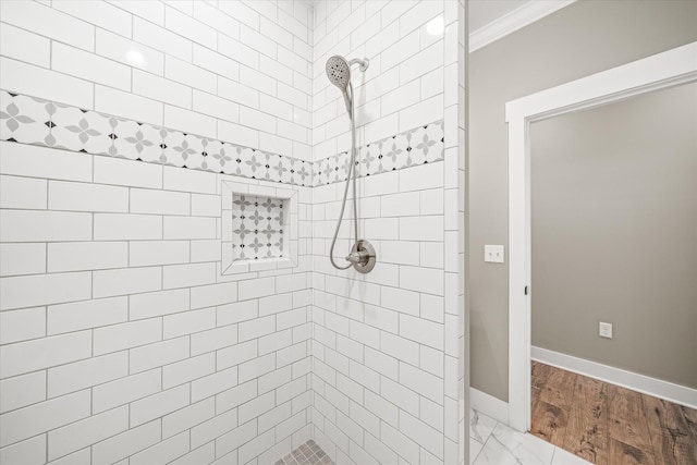 bathroom featuring crown molding, baseboards, and tiled shower