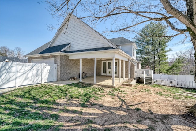 back of house featuring brick siding, fence, french doors, a patio area, and an attached garage