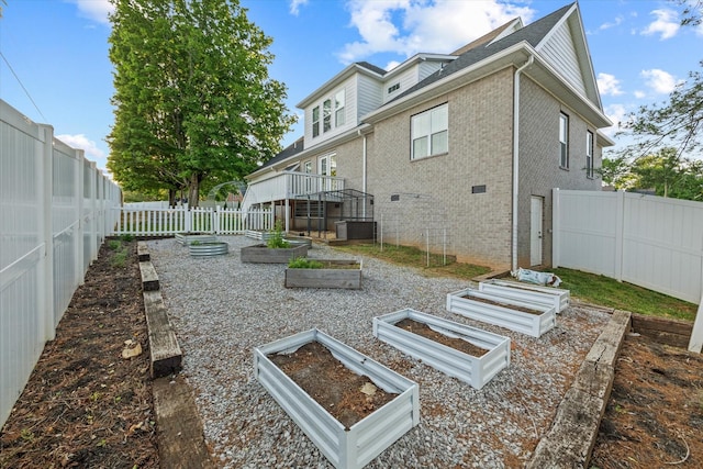 back of property featuring a fenced backyard, a vegetable garden, and brick siding