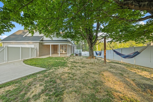 view of yard featuring a patio, a fenced backyard, and french doors