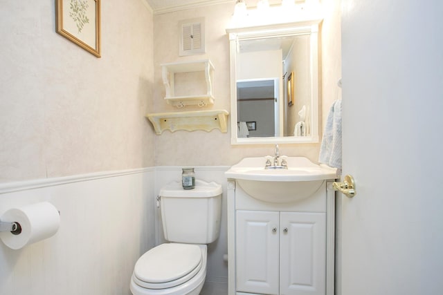 bathroom with vanity, a wainscoted wall, toilet, and visible vents