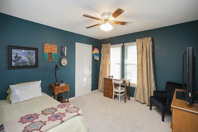 bedroom featuring baseboards, light carpet, a closet, a textured ceiling, and a ceiling fan