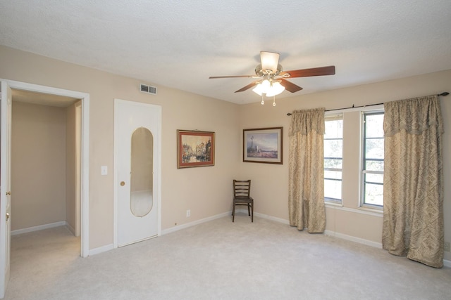 unfurnished room with visible vents, light carpet, a textured ceiling, baseboards, and ceiling fan