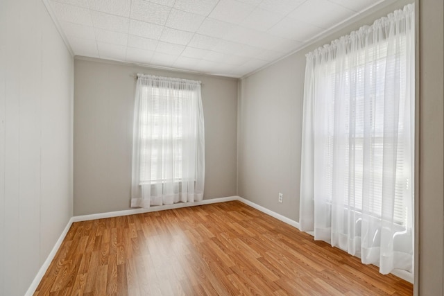 unfurnished room with baseboards, light wood finished floors, and ornamental molding