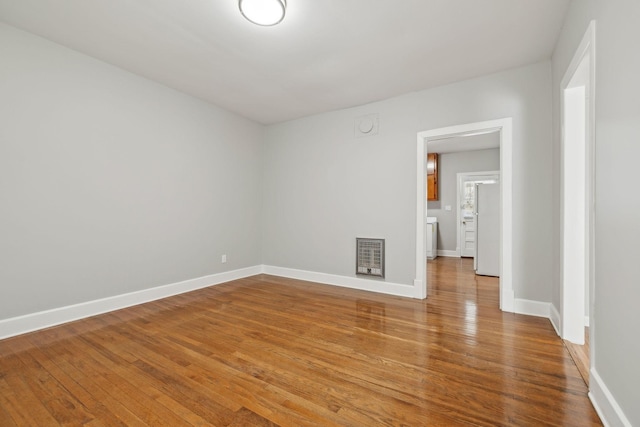 empty room with heating unit, baseboards, and wood-type flooring