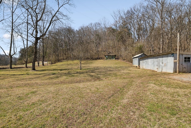 view of yard featuring an outbuilding and a view of trees