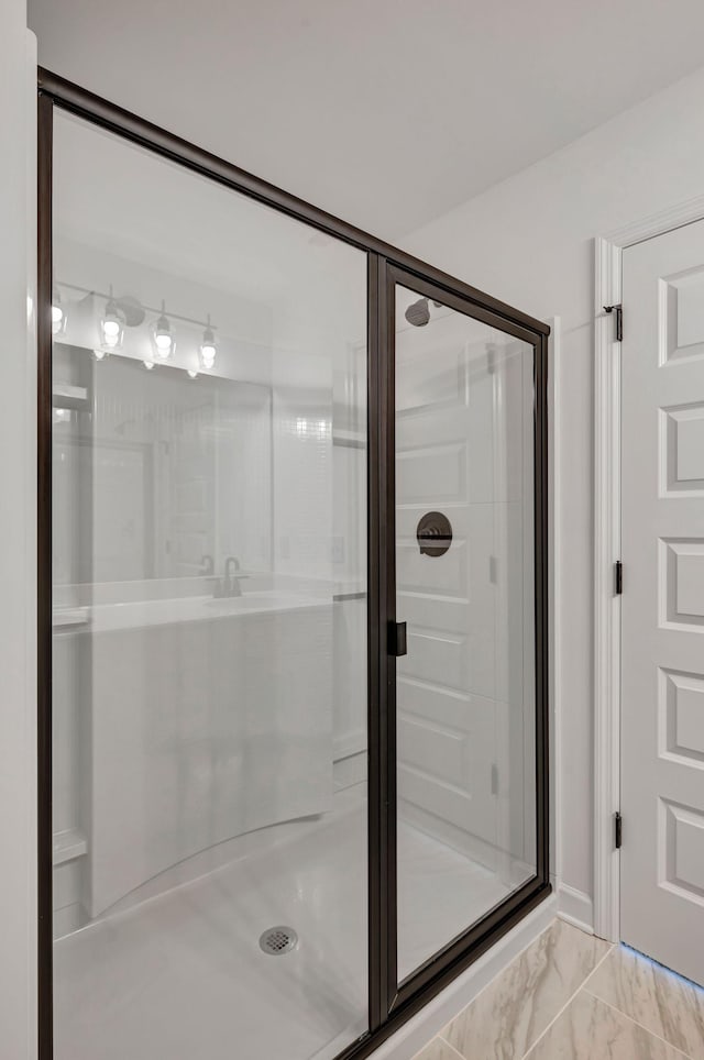 bathroom featuring marble finish floor and a stall shower