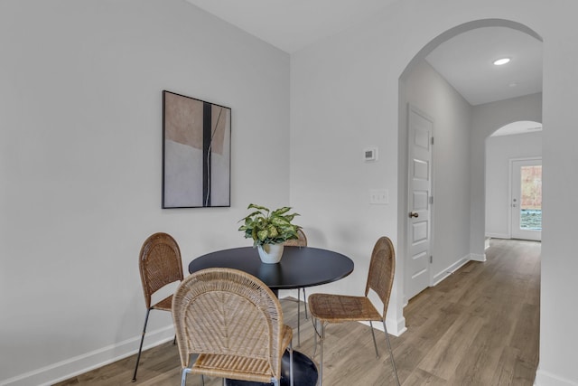 dining space with recessed lighting, wood finished floors, baseboards, and arched walkways