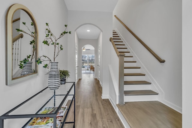 foyer entrance featuring stairway, wood finished floors, arched walkways, and baseboards