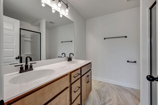 bathroom featuring marble finish floor, a shower stall, baseboards, and a sink