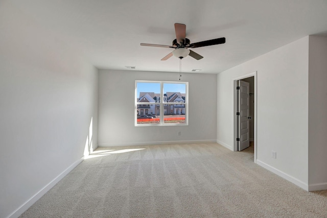 unfurnished room with light carpet, visible vents, a ceiling fan, and baseboards