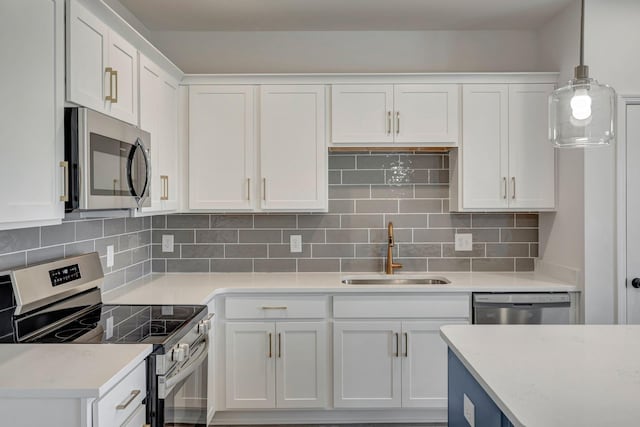 kitchen with a sink, backsplash, appliances with stainless steel finishes, white cabinets, and light countertops